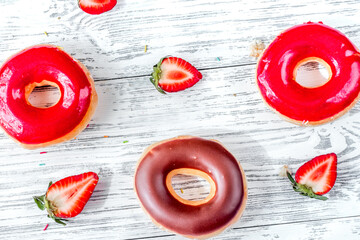 sweet colorful donuts with topping on wooden desk background top view