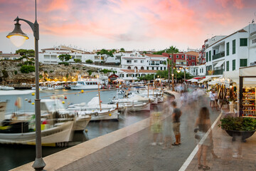 Menorca, Spain - 20 august 2021: people in the ES Castell harbor, at sunset touristic town with white architecture and buildings in Menorca, Spain during summer season.