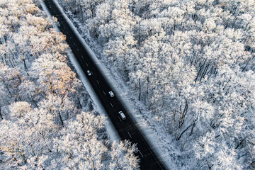 Wall Mural - cars traffic on a highway  along the frozen winter forest. seen from the air. Aerial view landscape. drone photography.