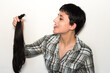 © AliciaFdez - Mujer joven con pelo corto sosteniendo su cabello cortado en una cola de caballo. Concepto de donación de cabello para pacientes con cáncer.