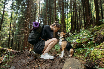 young woman hiking with a dog in the woods
