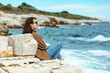 © phpetrunina14 - woman sitting on cliff enjoying view of the sea. windy weather. sunny day
