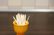 Close-up Shot Of Toothpicks In A Small Yellow Ceramic Bowl On A Wooden Table