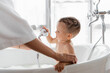 © LIGHTFIELD STUDIOS - tattooed mother holding shower head while bathing toddler son in bathroom
