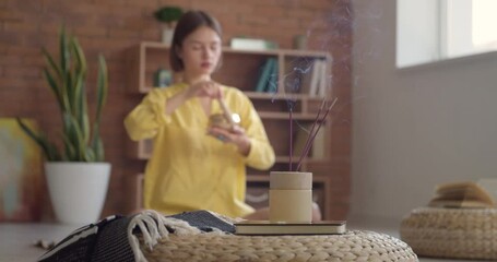 Poster - Burning incense sticks in room of young woman meditating with Tibetan singing bowl