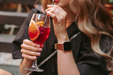 Crop female sipping cold non-alcoholic beverage through straw.