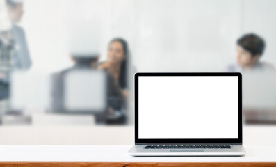 Mockup blank white screen laptop computer on white top table with blur background of business people.