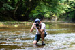 渓流で一眼レフカメラを構える男性