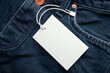 Cardboard tag on jeans texture with place for text. Empty label blank on cloth. Sale, discount and shopping concept
