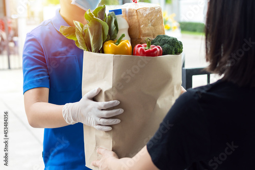 New normal. food delivery service man wearing protection face mask holding fresh food set bag to customer at door home, express delivery, new normal, virus outbreak, takeaway food delivery concept