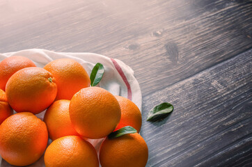 Fresh orange fruits with leaves on wooden table and sunlight morning.