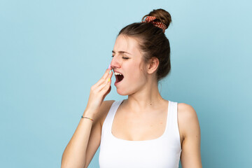 Wall Mural - Young caucasian woman isolated on blue background yawning and covering wide open mouth with hand