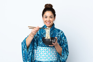 Woman wearing kimono over isolated white background holding a bowl of noodles with chopsticks