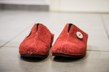 Poster - Close-up shot of beautiful red warm winter felt slippers on the floor