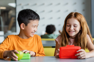 Wall Mural - redhead girl and smiling asian boy near lunch boxes in school dining room