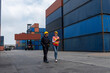 © InfiniteFlow - Industrial worker works with co-worker at overseas shipping container yard . Logistics supply chain management and international goods export concept .
