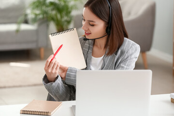 Wall Mural - Young woman with laptop and notebook at home