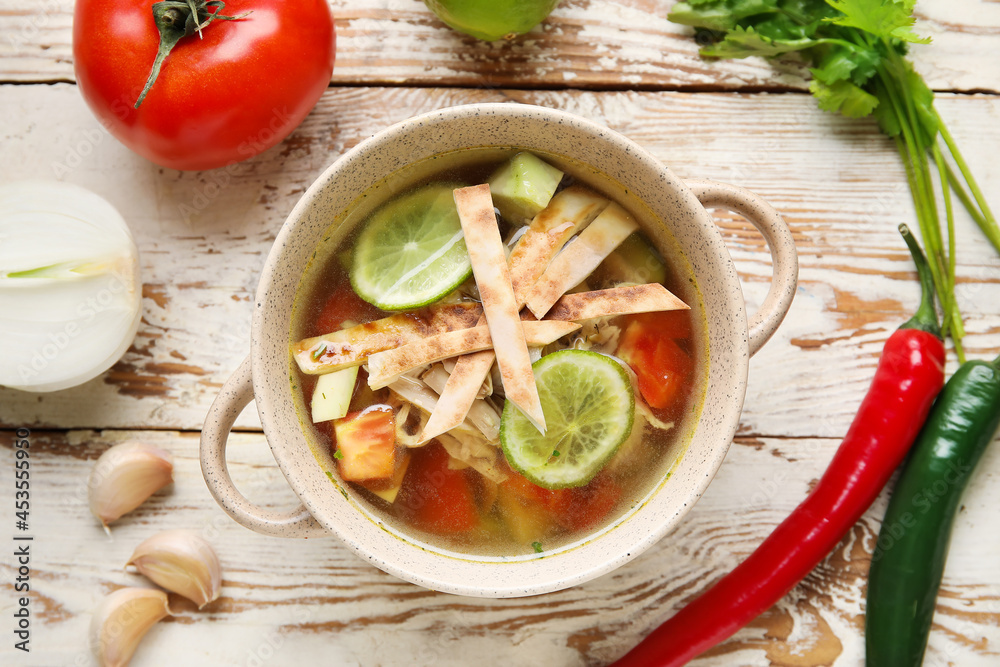 Composition with tasty Sopa de Lima soup on light wooden background