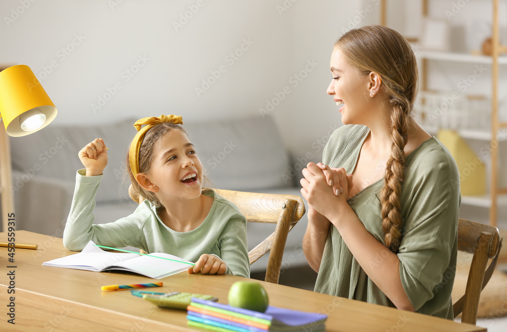 Little girl with her mother doing lessons at home