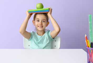 Poster - Little girl with notebooks and apple at table on color background