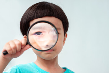 Boy focusing on magnifying glass He was serious about searching for something.