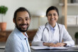 © fizkes - Smiling millennial healthy african american multiracial patient satisfied with visiting indian female doctor, looking at camera in modern clinic office room, medical insurance healthcare concept.