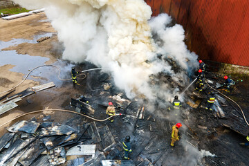 Aerial view of firefighters extinguishing fire in industrial area.