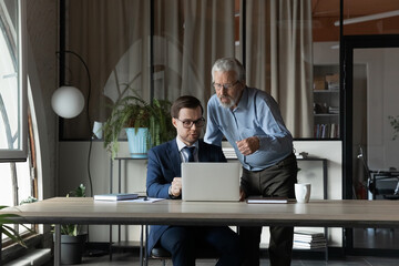 Sticker - Senior businessman wearing glasses mentor instructing training new employee, using laptop, helping with corporate software, two colleagues working on online project together, discussing strategy