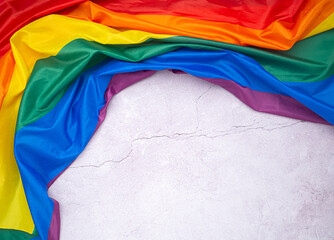 The rainbow flag (LGBT) is on a cement floor with space for text. Top view. Flat lay. Love concept