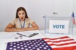 © Krakenimages.com - Young brunette woman at political election sitting by ballot scared and amazed with open mouth for surprise, disbelief face