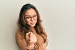 Young hispanic girl wearing casual clothes and glasses beckoning come here gesture with hand inviting welcoming happy and smiling