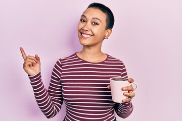 Wall Mural - Beautiful hispanic woman with short hair drinking a cup of coffee smiling happy pointing with hand and finger to the side