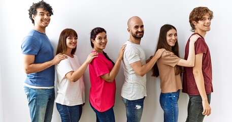 Poster - Group of young friends standing together over isolated background looking to side, relax profile pose with natural face and confident smile.