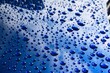 Raindrops on a blue car body with hydrophobic effect.