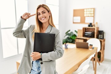 Sticker - Blonde business woman at the office smiling pointing to head with one finger, great idea or thought, good memory