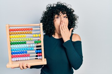 Poster - Young middle east woman holding traditional abacus covering mouth with hand, shocked and afraid for mistake. surprised expression