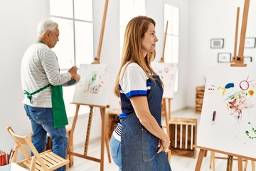 Poster - Hispanic woman wearing apron at art studio looking to side, relax profile pose with natural face with confident smile.