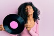 © Krakenimages.com - African american woman with afro hair holding vinyl disc looking at the camera blowing a kiss being lovely and sexy. love expression.