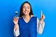 © Krakenimages.com - Young hispanic girl holding sand clock smiling with an idea or question pointing finger with happy face, number one