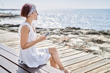 Poster - Young caucasian girl using smartphone sitting on the bench at the beach.