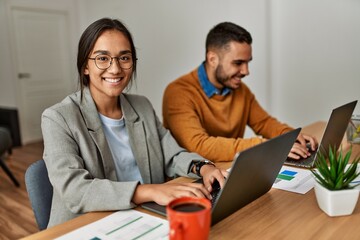 Wall Mural - Two business workers smiling happy working sitting on desk at the office.