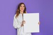 © Evgenia - Young caucasian student girl holding a white sheet of paper, poster, placard in hands smiling isolated on lilac background