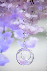 Canvas Print - Creative glass toy with a candle inside is hanging on the flowers