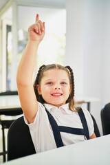 Wall Mural - Little spanish school girl raising hand in class to intervene