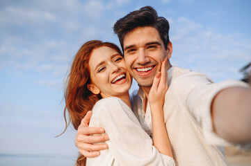 Wall Mural - Close up satisfied happy young couple two family man woman wear white clothes hug each other do selfie shot pov on mobile phone at sunrise over sea beach outdoor seaside in summer day sunset evening