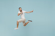 Full length side view young happy man 20s wear casual white t-shirt jump high point index finger aside on workspace area mock up isolated on plain pastel light blue color background studio portrait