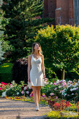 Sticker - Caucasian young woman walking down at alley with flowers in a garden