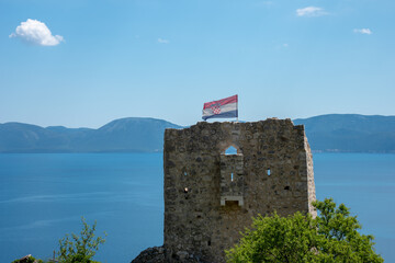 Ruins of the tower on the top of the hill. Flag on the wind. Podaca Village, Makarska Riviera, Dalmatia Croatia. Shore of Adriatic Sea. 