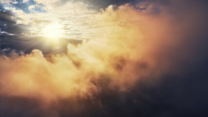Wall Mural - flying through amazing yellow and orange sunset clouds towards bright shining sun. view from airplan