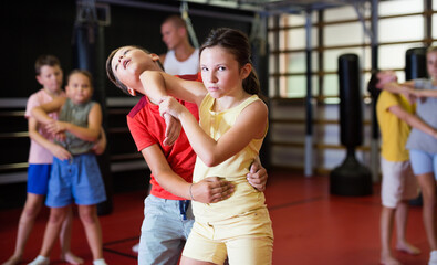 Wall Mural - Girls and boys training chin strike on each other during group self-protection training.